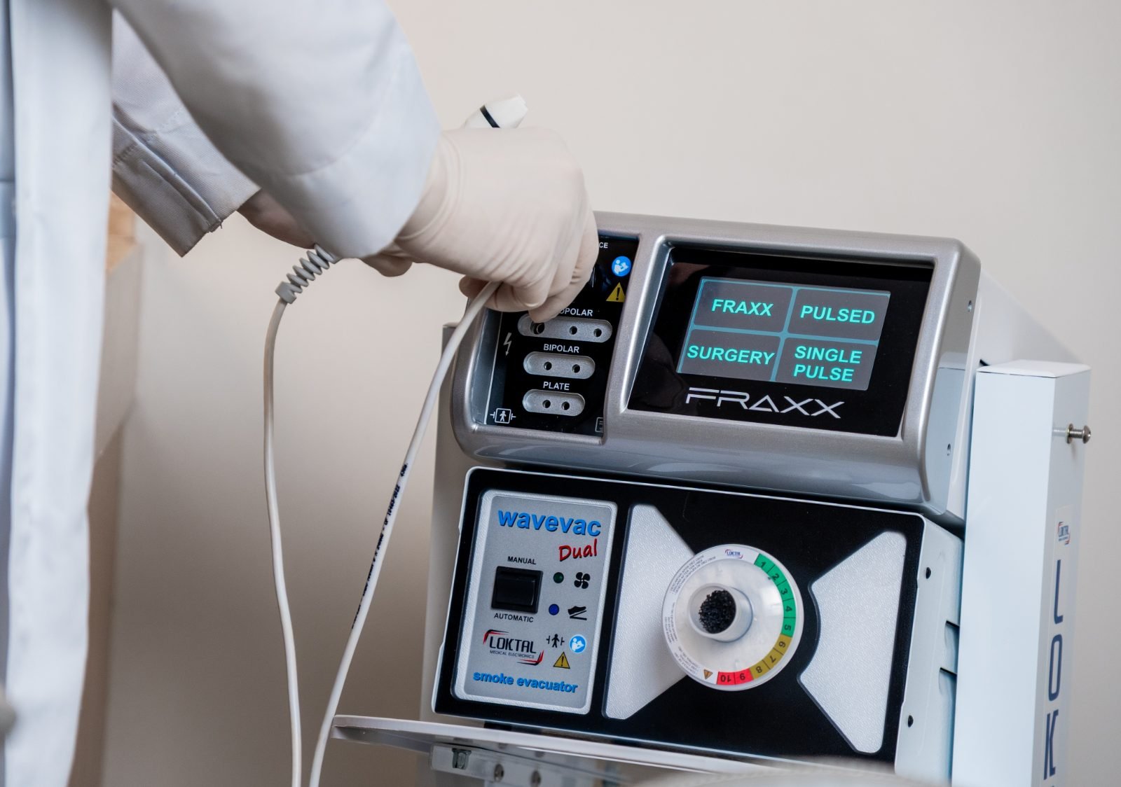 Mão enluvada da profissional segurando o handpiece do FRAXX
